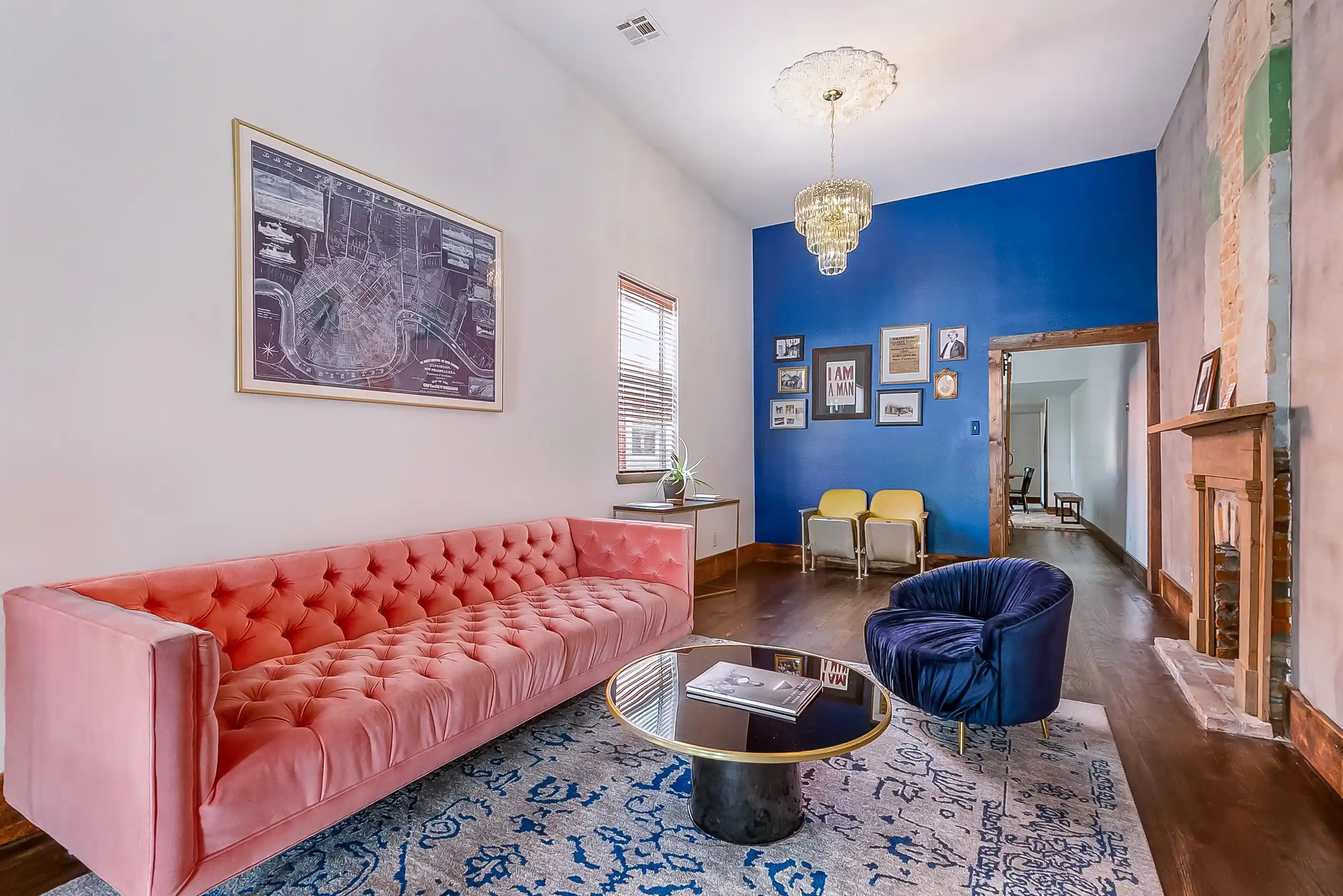 living room with a pink couch, blue velvet chair, and blue & white rug