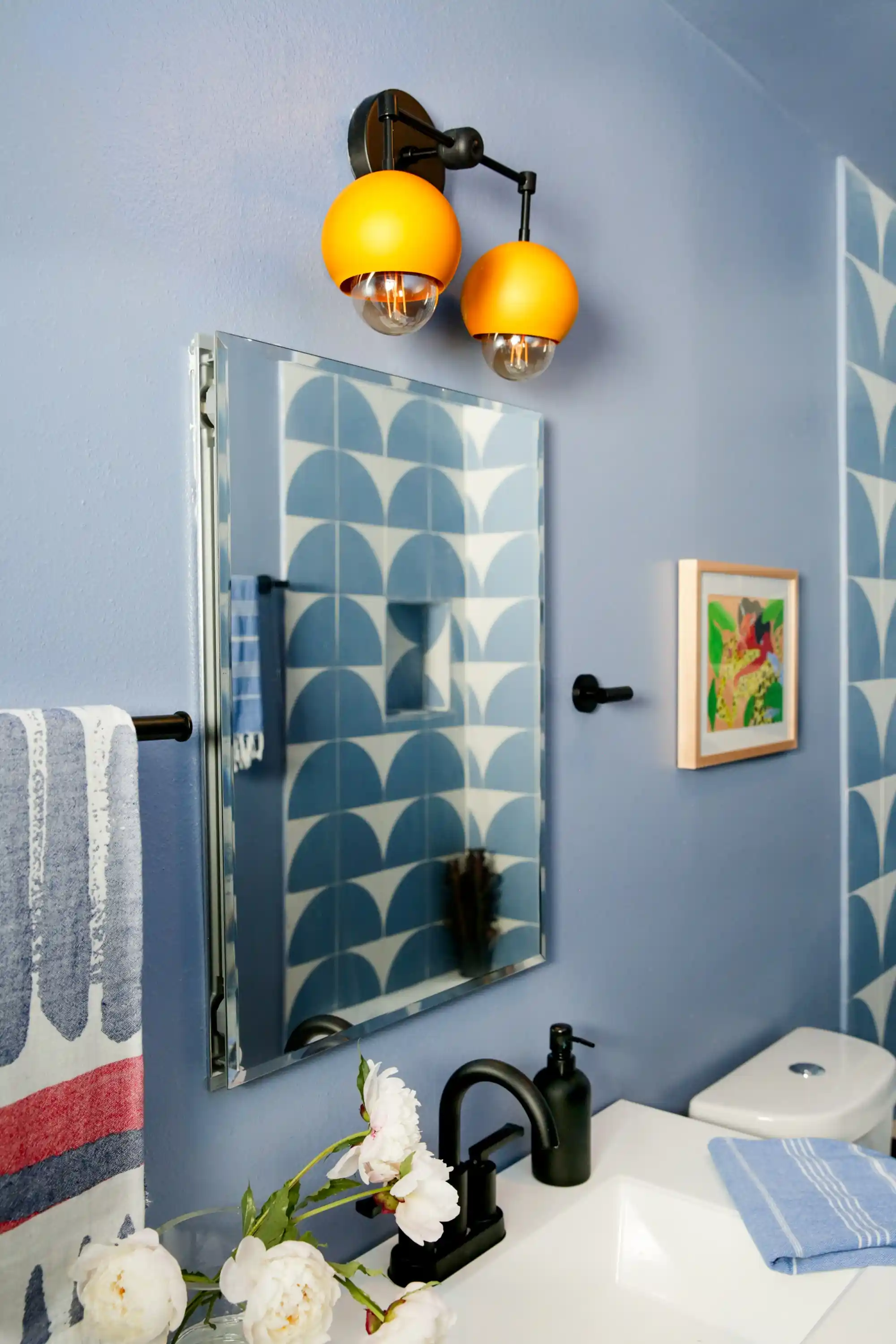 bathroom with light blue walls, yellow lights, and white sinks